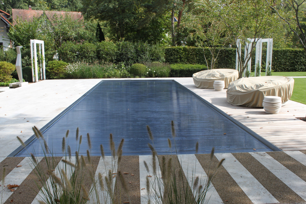 Inspiration for a large country side rectangular swimming pool in Frankfurt with natural stone paving.