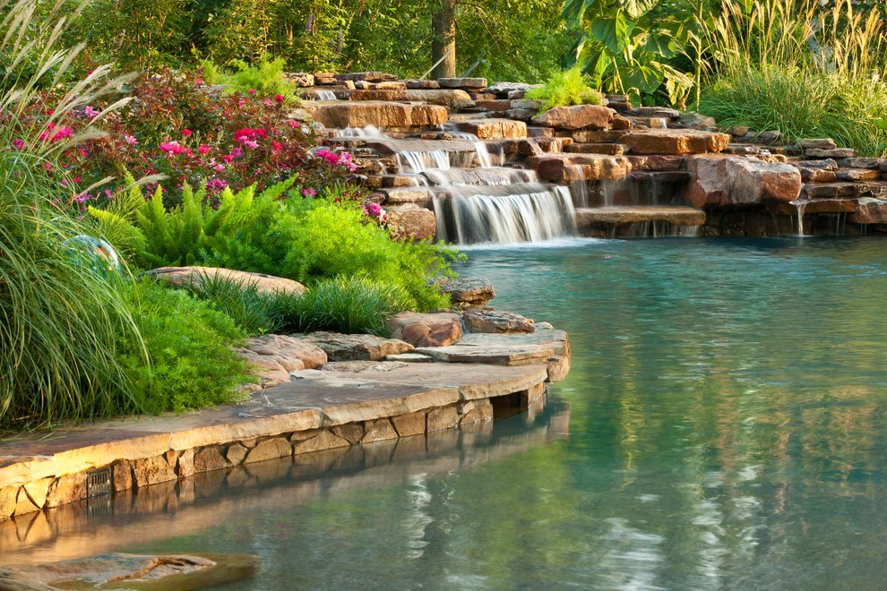 Diseño de piscina con fuente natural exótica grande a medida en patio trasero con adoquines de piedra natural