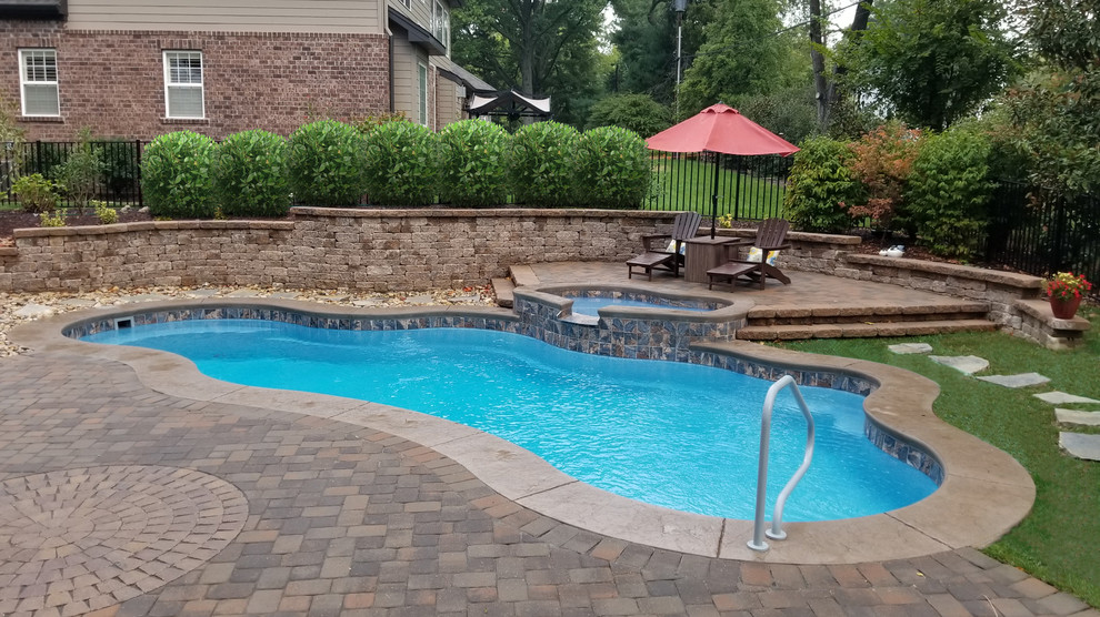 Imagen de piscina clásica grande a medida en patio trasero con suelo de hormigón estampado