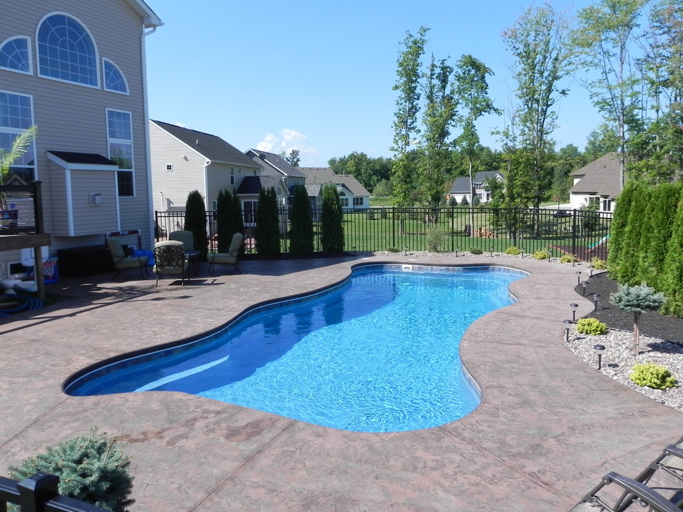 Ejemplo de piscinas y jacuzzis naturales de estilo americano grandes a medida en patio trasero con adoquines de piedra natural