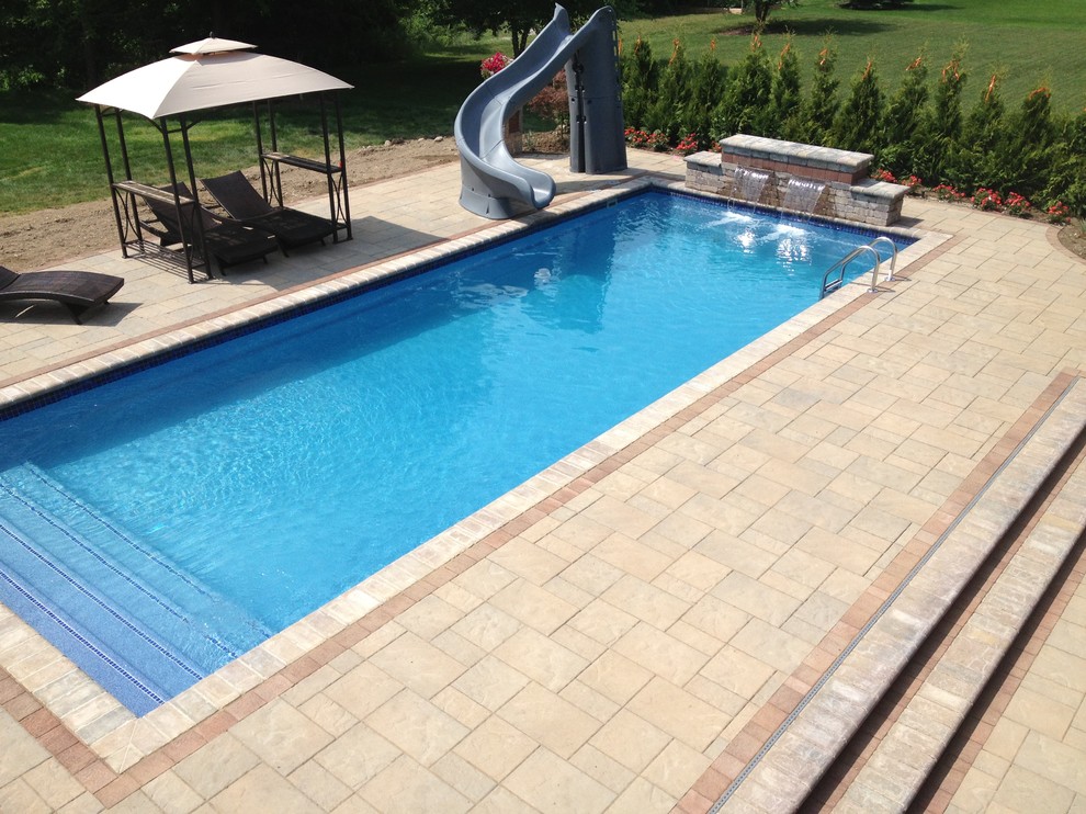 Immagine di una piscina tradizionale rettangolare dietro casa con pavimentazioni in mattoni e fontane