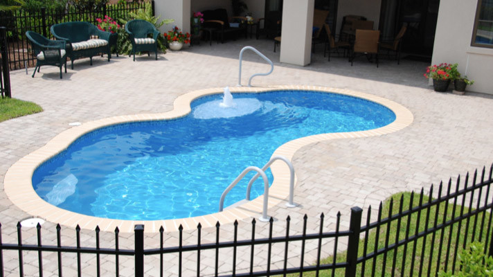 Immagine di una piscina classica personalizzata dietro casa con pavimentazioni in mattoni