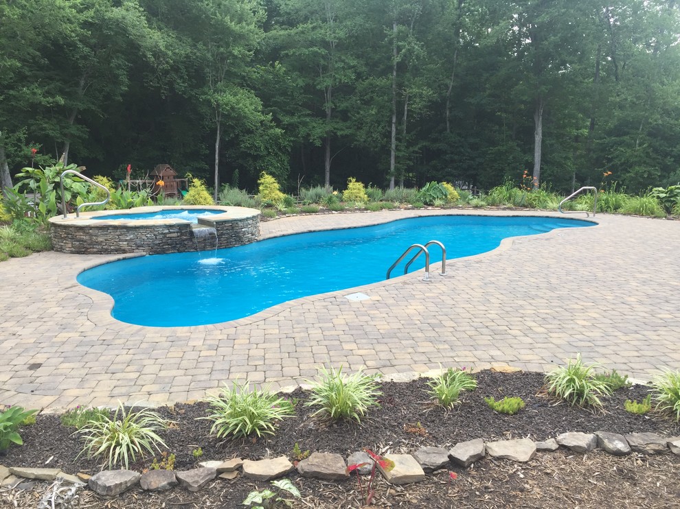 Ejemplo de piscinas y jacuzzis naturales rústicos grandes a medida en patio trasero con adoquines de hormigón