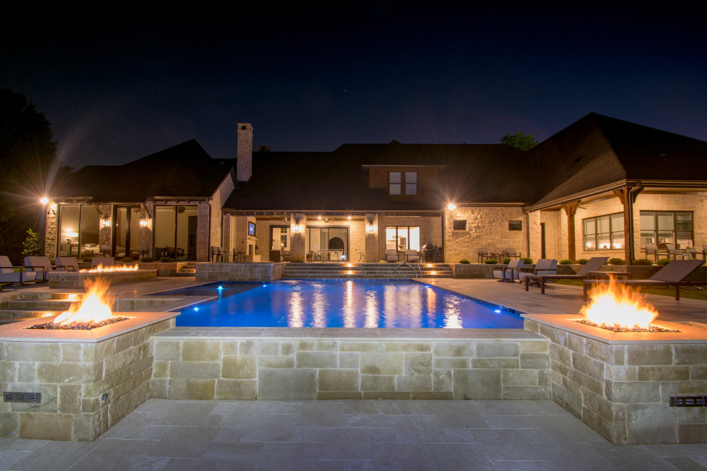 Example of a large farmhouse backyard stone and custom-shaped lap pool fountain design in Dallas