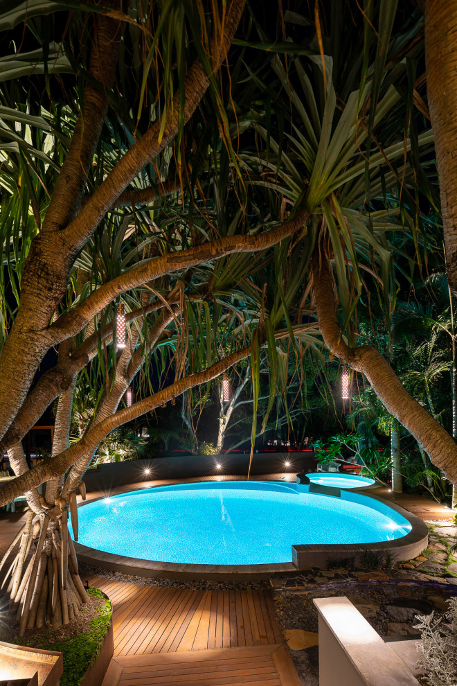 Ispirazione per una piscina tropicale rotonda con una vasca idromassaggio