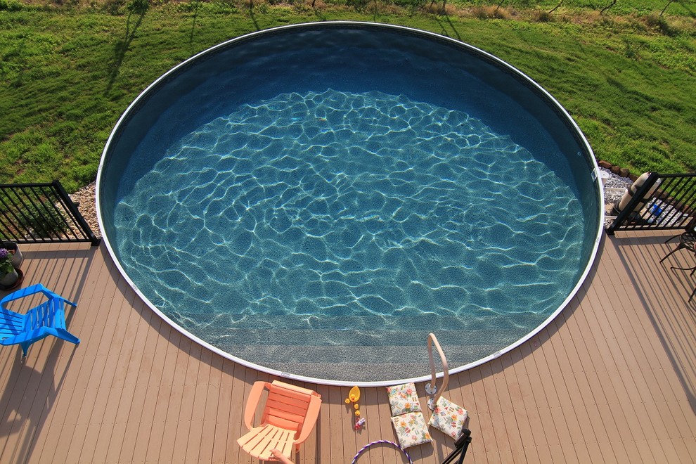 Imagen de piscina elevada mediterránea redondeada en patio trasero con losas de hormigón
