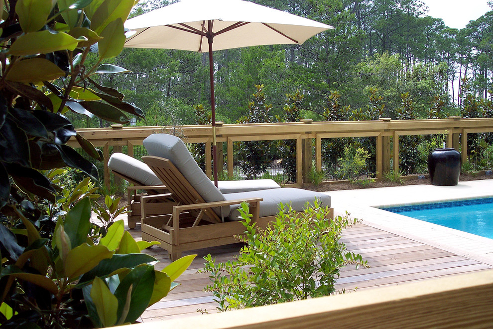Diseño de piscina con fuente alargada costera de tamaño medio rectangular en patio trasero con adoquines de hormigón