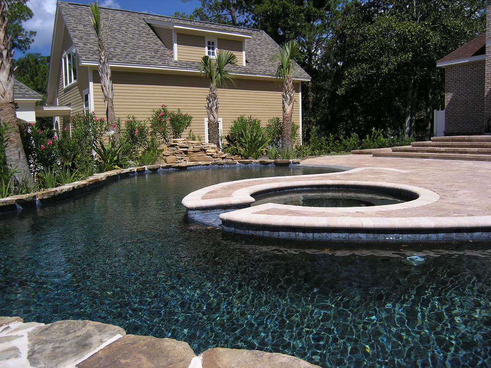 Esempio di una grande piscina a sfioro infinito classica personalizzata dietro casa con pavimentazioni in cemento e una vasca idromassaggio