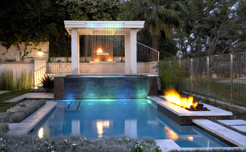 Imagen de piscina con fuente alargada contemporánea grande rectangular en patio trasero con adoquines de hormigón