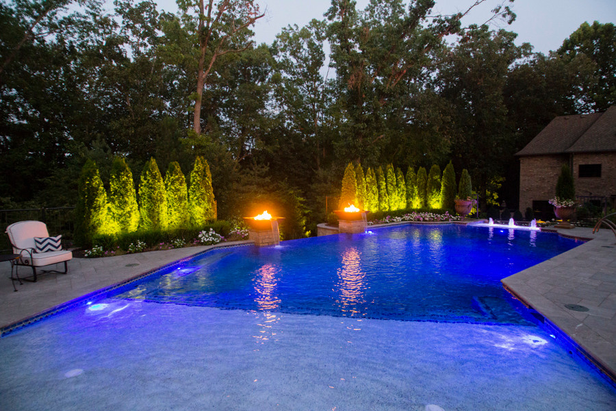 Immagine di una grande piscina a sfioro infinito contemporanea personalizzata dietro casa con fontane
