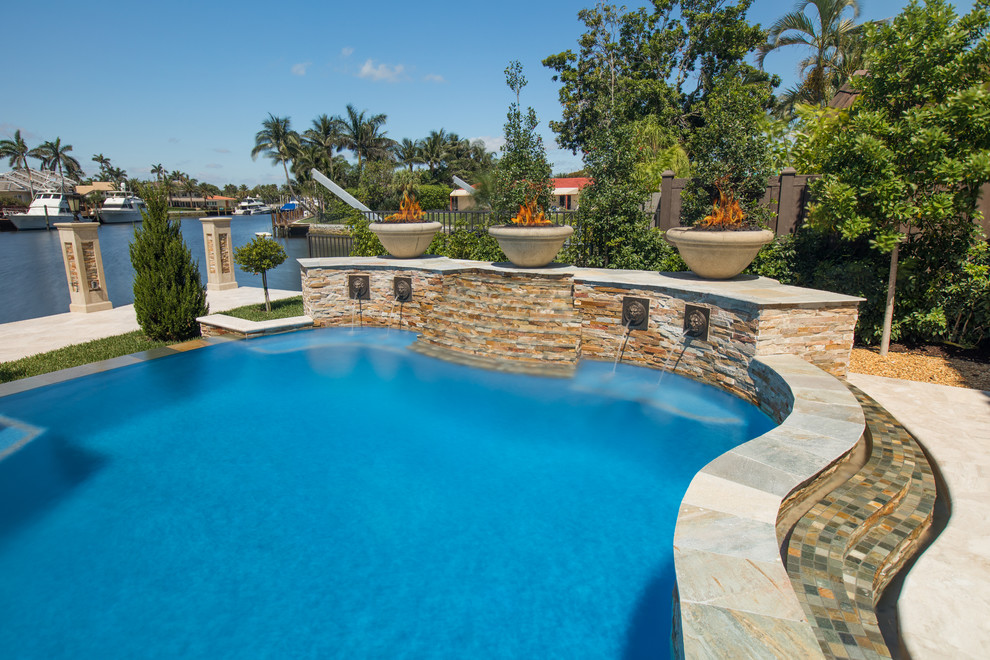 Пример оригинального дизайна: огромный естественный бассейн произвольной формы на заднем дворе в современном стиле с покрытием из каменной брусчатки