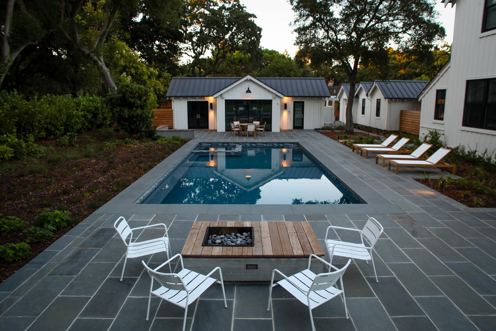 Bild på en stor lantlig rektangulär pool på baksidan av huset, med poolhus och naturstensplattor