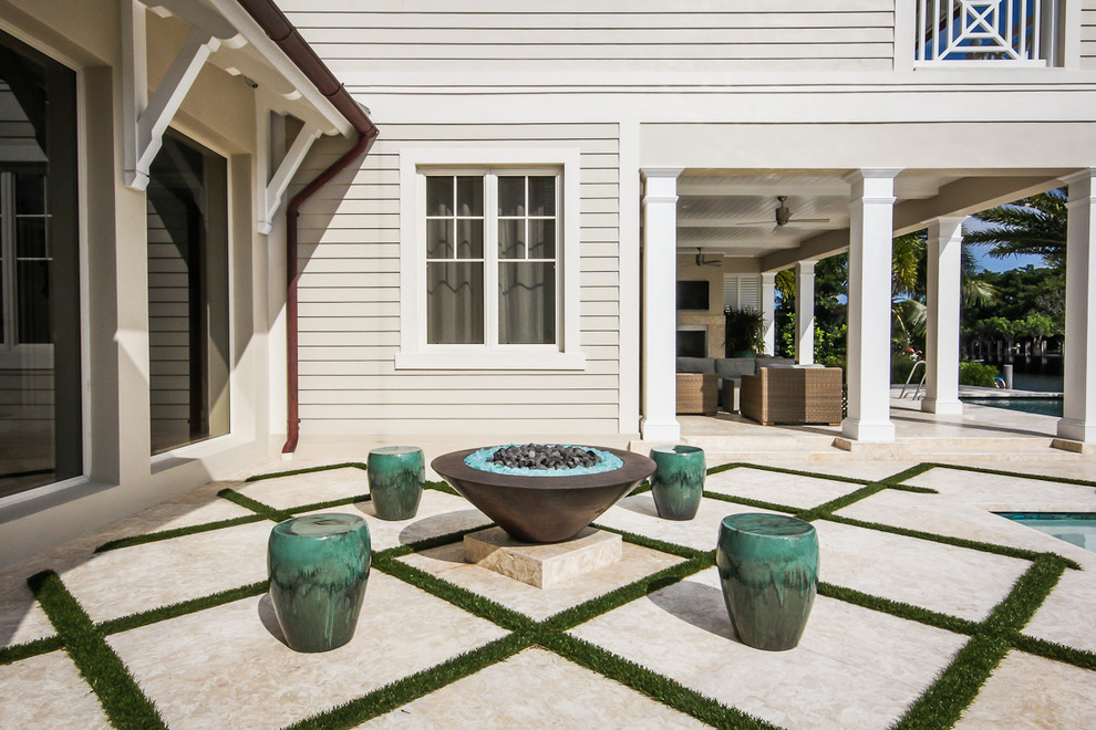 Large modern back rectangular lengths swimming pool in Miami with a water feature and natural stone paving.