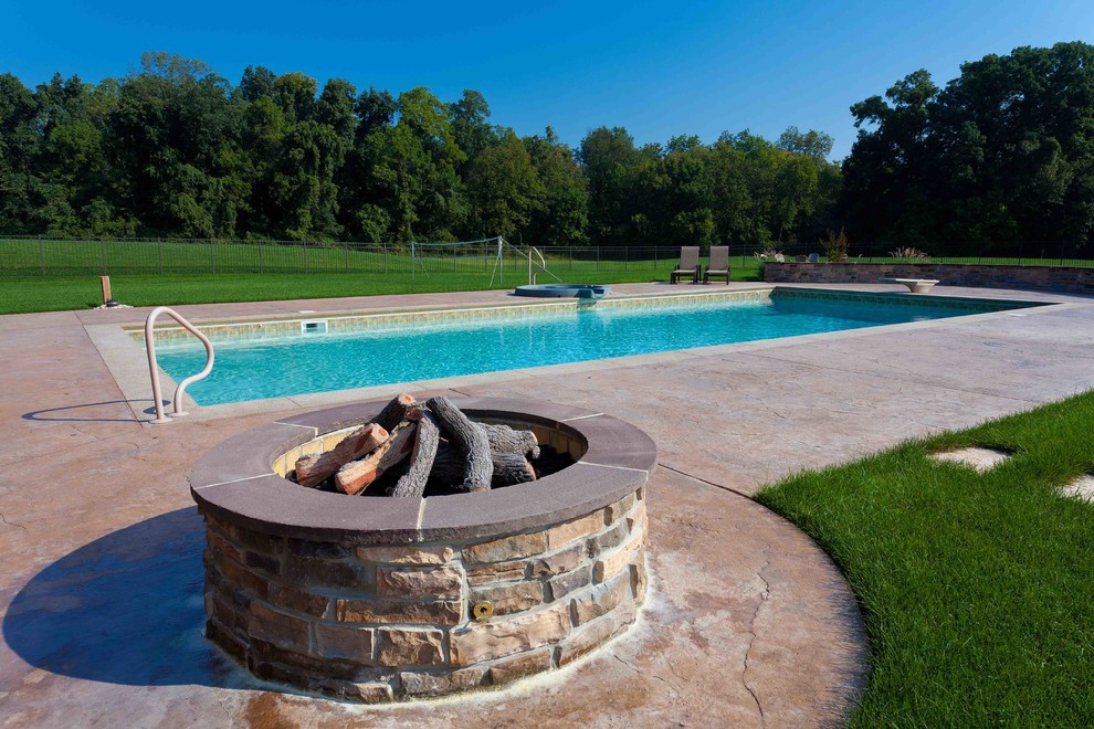 Imagen de piscina alargada campestre grande rectangular en patio trasero con adoquines de hormigón