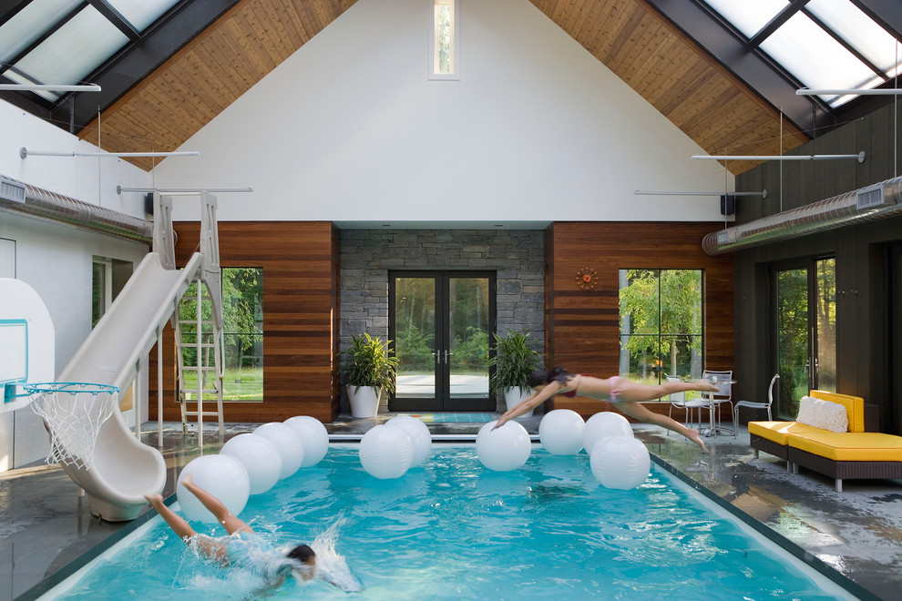 Ispirazione per una piscina coperta moderna rettangolare con un acquascivolo e pavimentazioni in pietra naturale