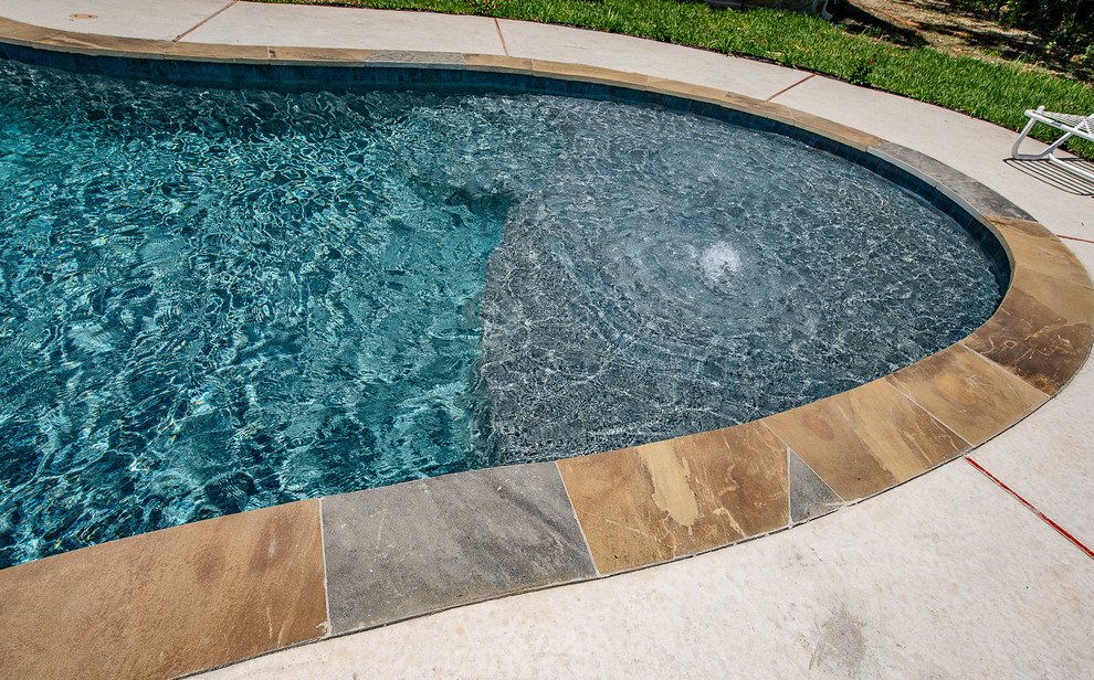 This is an example of a medium sized rustic back custom shaped natural hot tub in Other with natural stone paving.