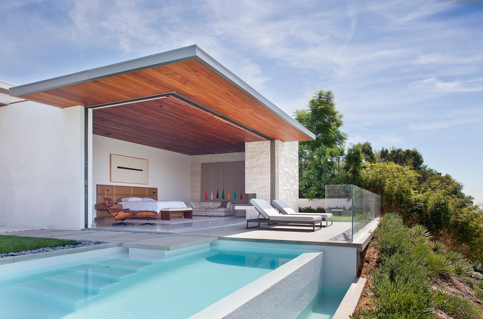 Diseño de casa de la piscina y piscina infinita contemporánea rectangular en patio trasero con losas de hormigón