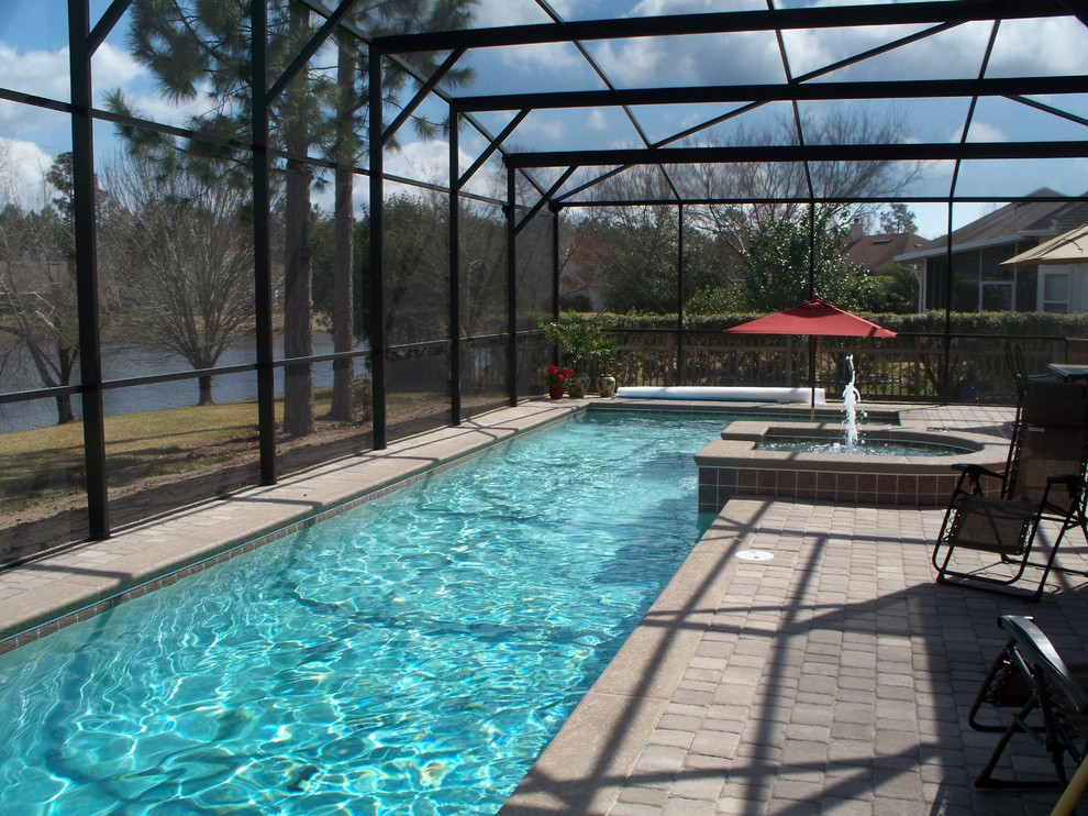 Foto de piscinas y jacuzzis alargados actuales grandes en forma de L en patio trasero con adoquines de hormigón