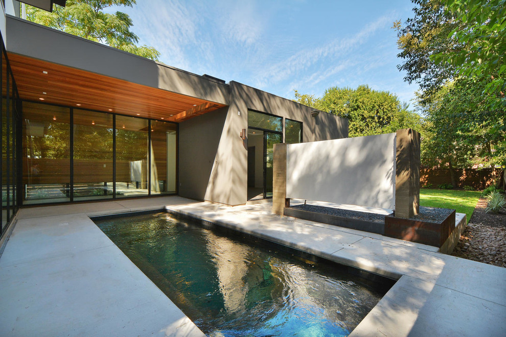 Ispirazione per una piccola piscina monocorsia design rettangolare dietro casa con pavimentazioni in cemento