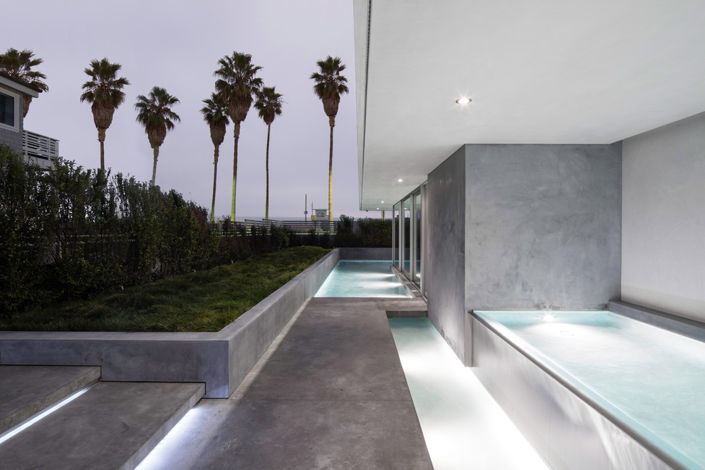 Medium sized modern front custom shaped infinity swimming pool in Los Angeles with a water feature and concrete slabs.