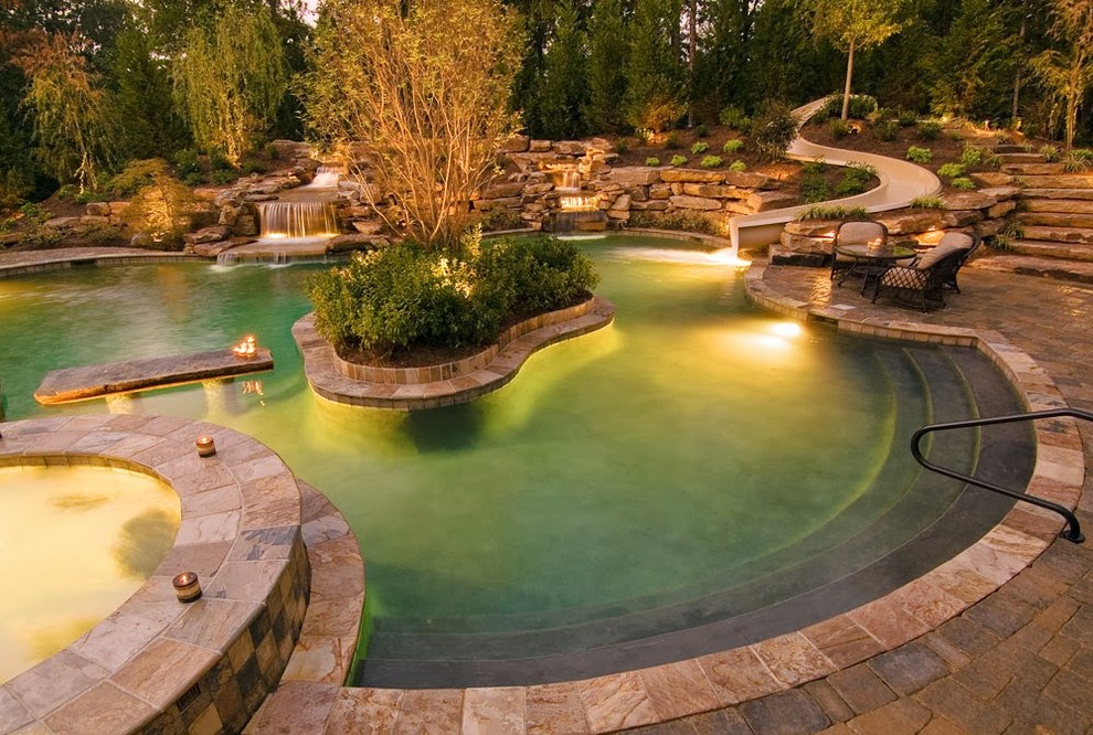 Immagine di una piscina a sfioro infinito tropicale personalizzata di medie dimensioni e dietro casa con un acquascivolo e pavimentazioni in pietra naturale