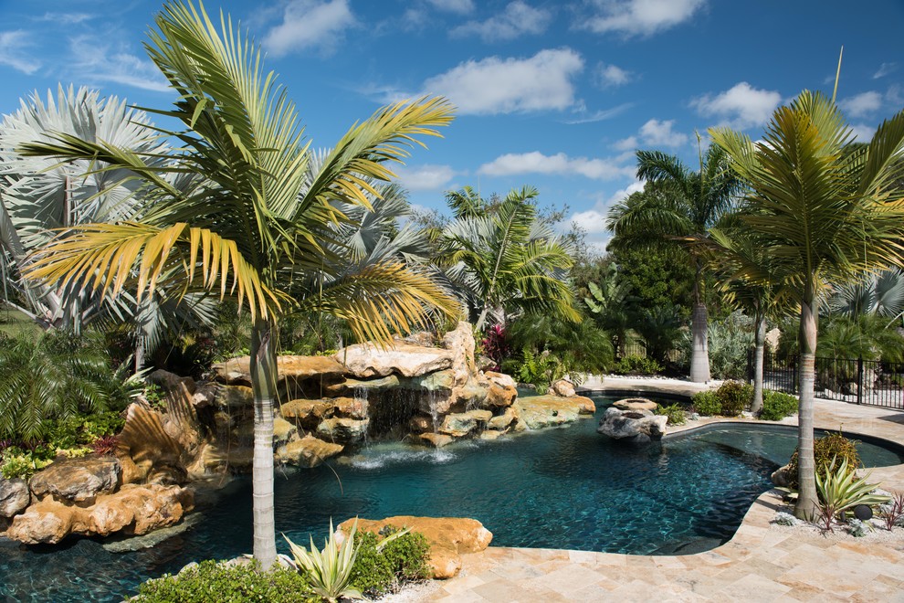Modelo de piscina con fuente tropical de tamaño medio a medida en patio trasero con adoquines de piedra natural