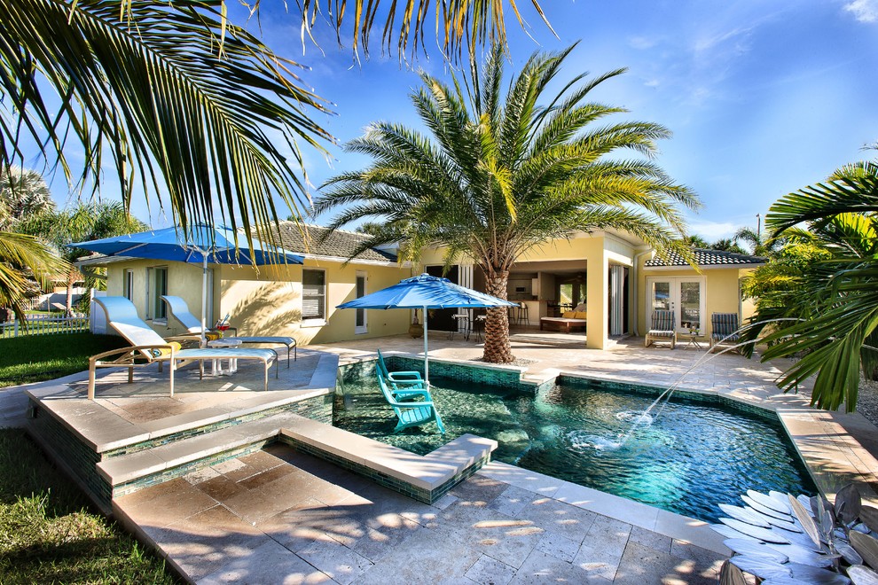 Esempio di una piccola piscina tropicale personalizzata dietro casa con fontane e piastrelle