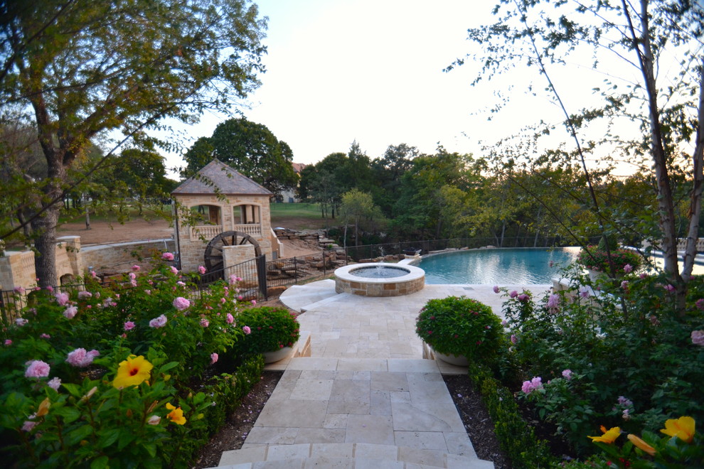 Idee per un'ampia piscina a sfioro infinito chic personalizzata dietro casa con fontane e pavimentazioni in pietra naturale