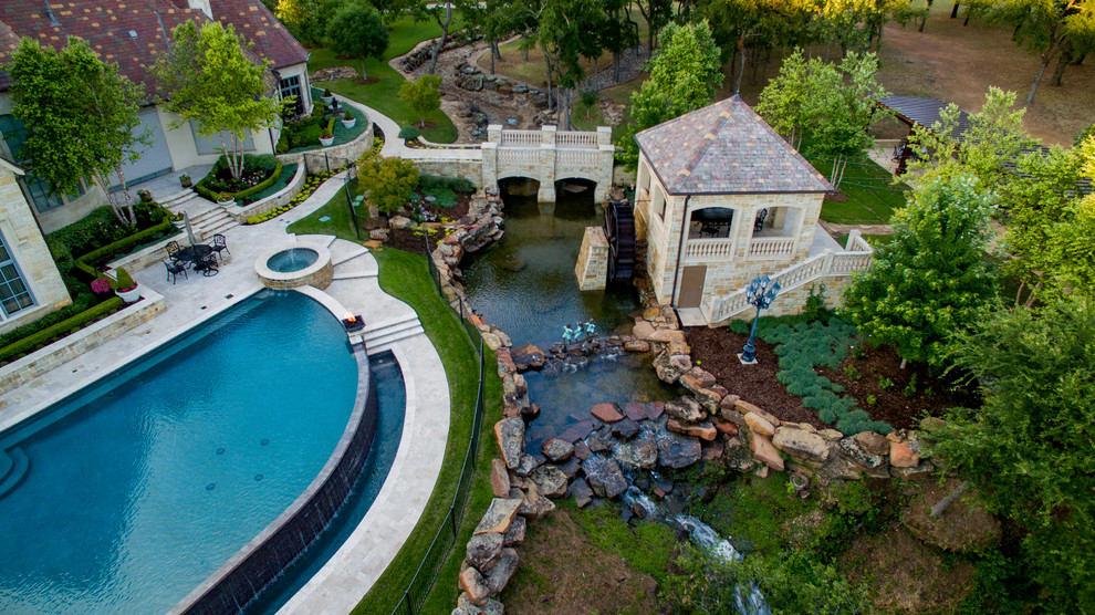 Idée de décoration pour une très grande piscine à débordement et arrière tradition sur mesure avec un point d'eau et des pavés en pierre naturelle.