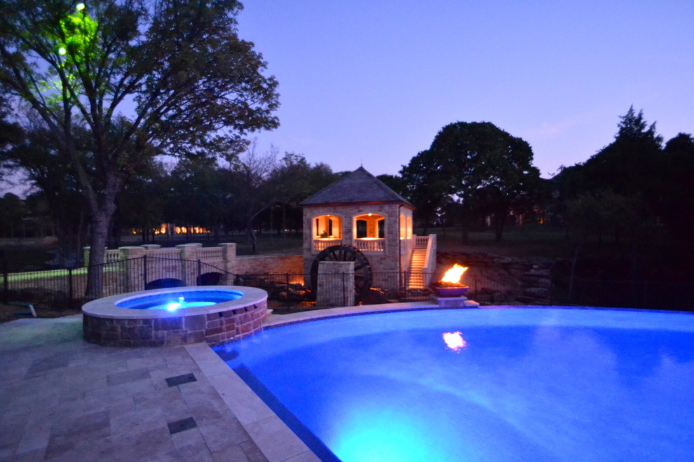 Design ideas for an expansive classic back custom shaped infinity swimming pool in Dallas with a water feature and natural stone paving.