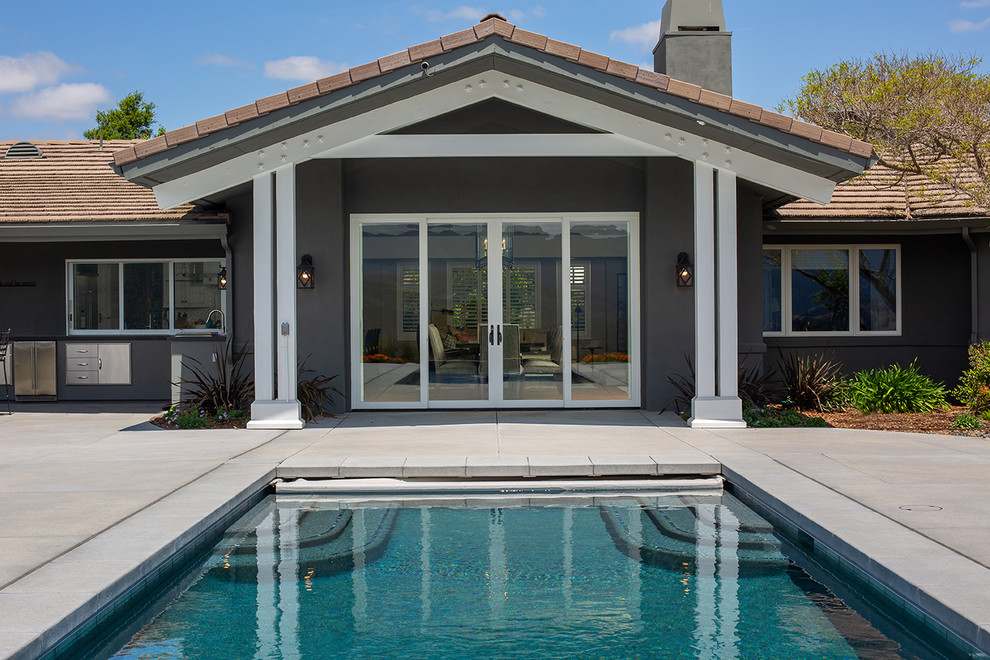 Immagine di una piscina country rettangolare di medie dimensioni e dietro casa con lastre di cemento