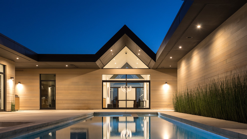 Foto de piscina alargada minimalista rectangular en patio trasero con adoquines de hormigón