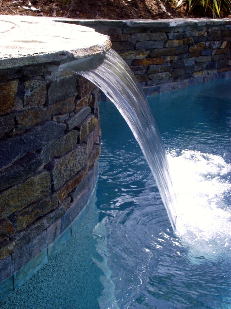 サクラメントにある中くらいなトロピカルスタイルのおしゃれな裏庭プール (噴水、天然石敷き) の写真