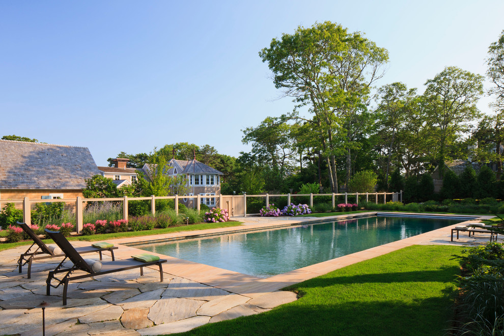 Immagine di una grande piscina monocorsia tradizionale rettangolare dietro casa con pavimentazioni in pietra naturale