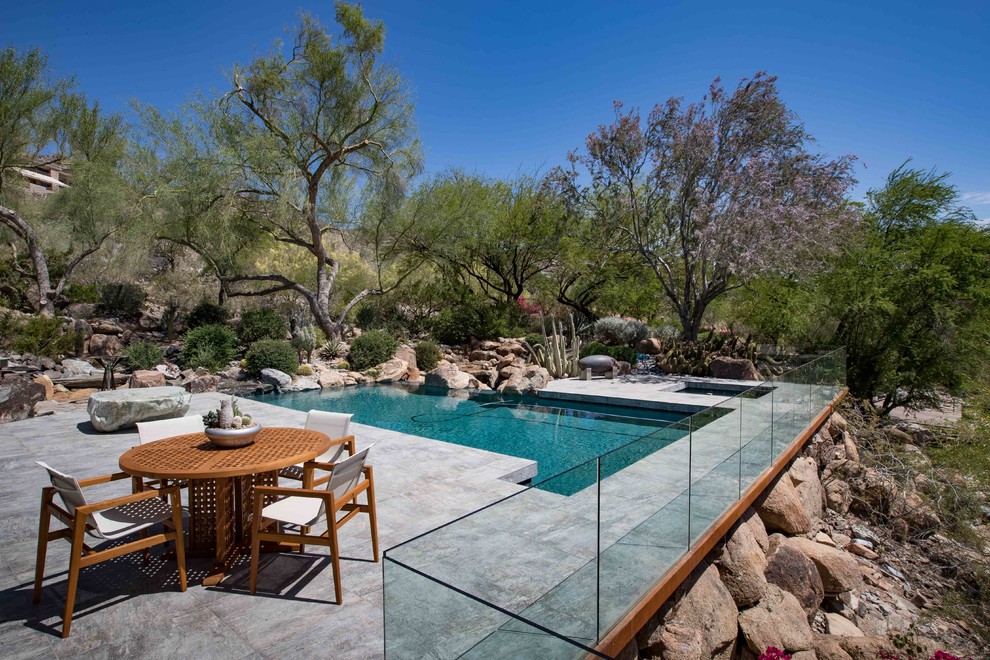 Foto di una grande piscina monocorsia design rettangolare dietro casa con piastrelle e una vasca idromassaggio