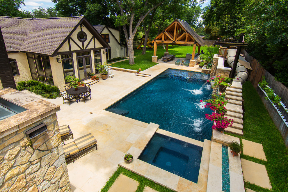 Modelo de piscina con tobogán alargada de estilo de casa de campo grande rectangular en patio lateral con adoquines de piedra natural