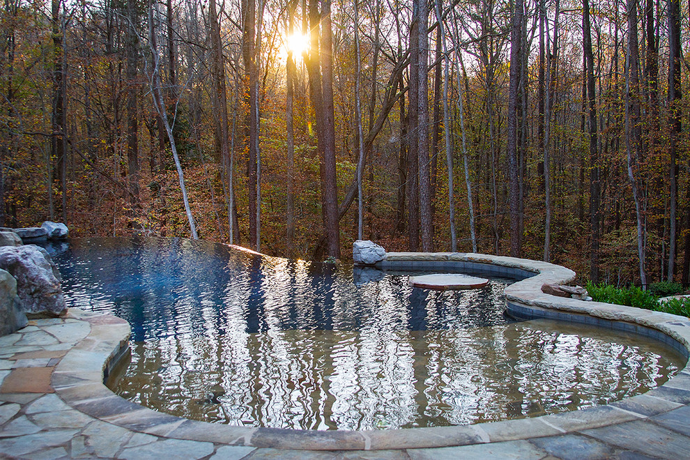Идея дизайна: большой бассейн-инфинити произвольной формы на заднем дворе в стиле рустика с фонтаном и покрытием из каменной брусчатки