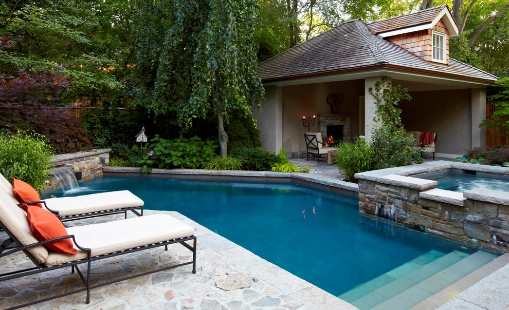 На фото: угловой бассейн на заднем дворе в классическом стиле с домиком у бассейна и покрытием из каменной брусчатки с