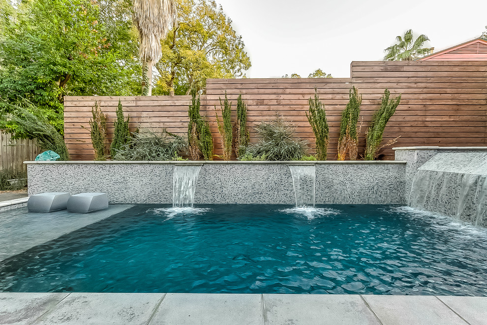 Ejemplo de piscina con fuente natural moderna de tamaño medio rectangular en patio con suelo de baldosas
