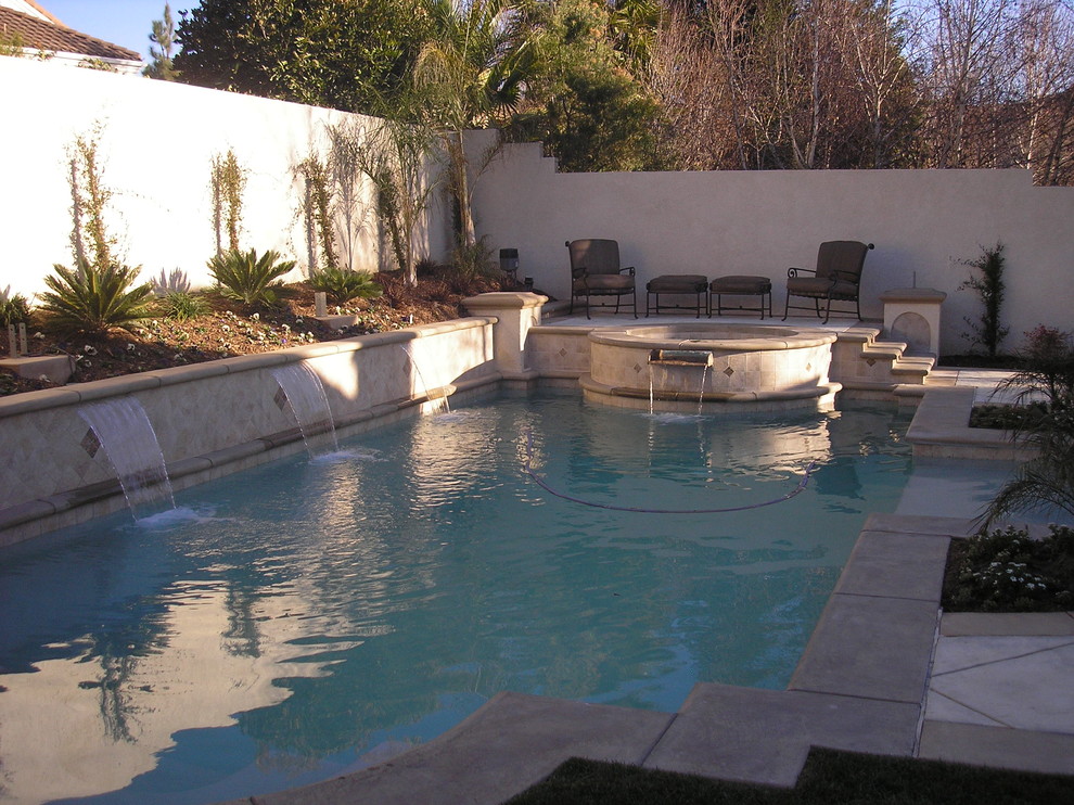 На фото: бассейн среднего размера, произвольной формы на заднем дворе в классическом стиле с джакузи и мощением тротуарной плиткой