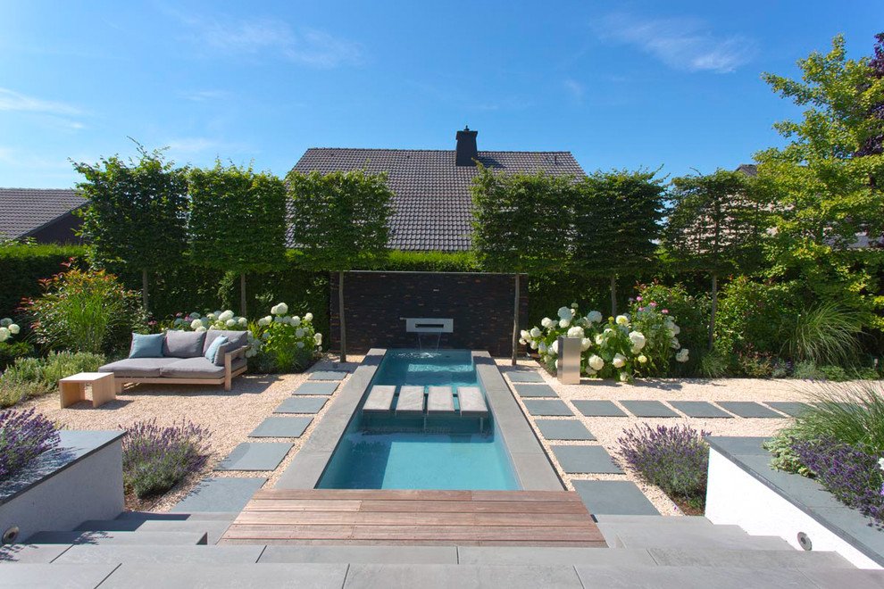 Kleiner Moderner Pool hinter dem Haus in rechteckiger Form mit Wasserspiel und Betonplatten in Sonstige