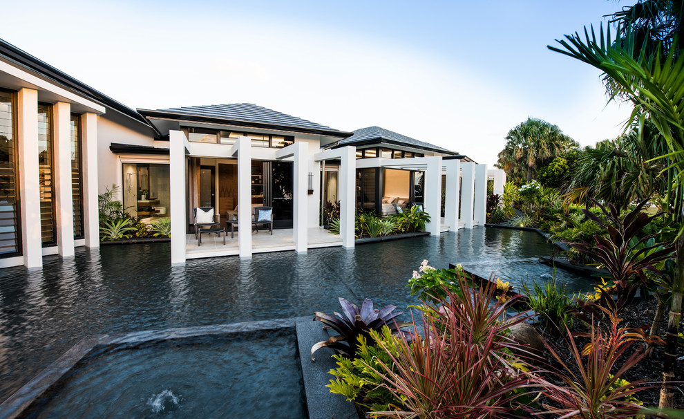 Inspiration för en tropisk anpassad pool på baksidan av huset, med spabad