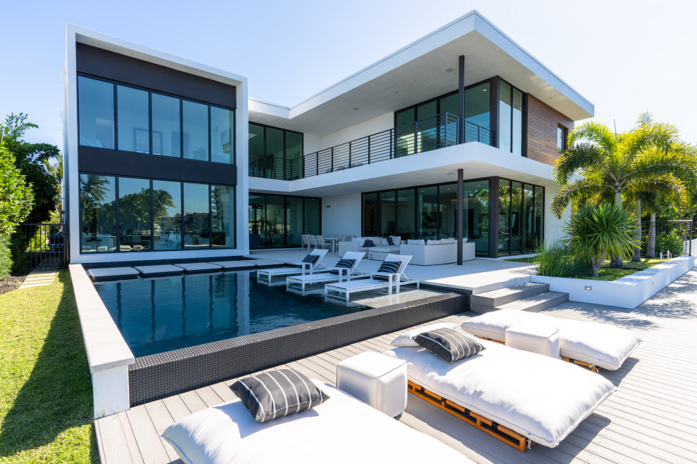 Large trendy backyard rectangular pool photo in Miami with decking