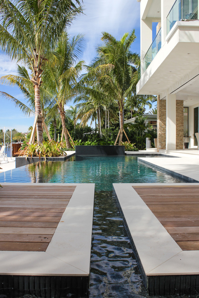 Ispirazione per una grande piscina a sfioro infinito minimal personalizzata dietro casa con una vasca idromassaggio e pedane