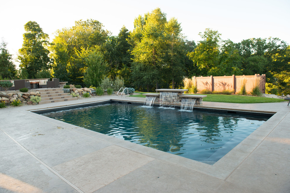 Cette image montre une piscine arrière design de taille moyenne et rectangle avec un point d'eau et du béton estampé.