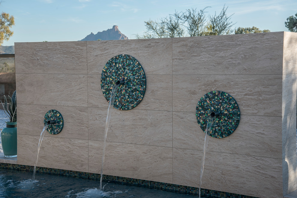 Photo of a large contemporary back rectangular lengths swimming pool in Phoenix with a water feature and natural stone paving.