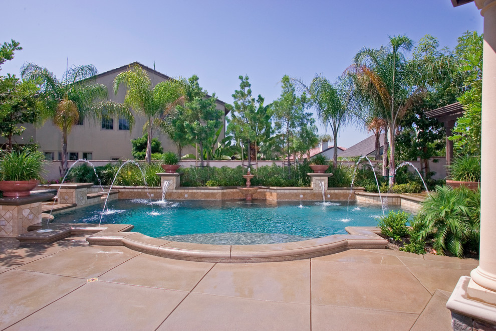 Diseño de piscina con fuente clásica grande a medida en patio trasero con adoquines de hormigón