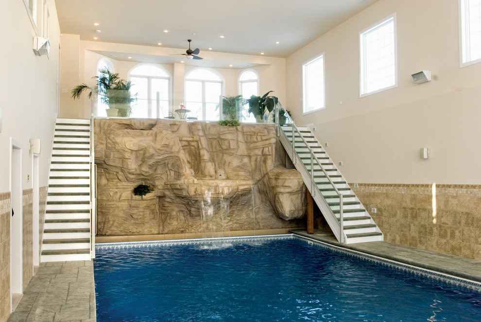 Cette image montre une grande piscine intérieure ethnique rectangle avec un point d'eau et des pavés en pierre naturelle.