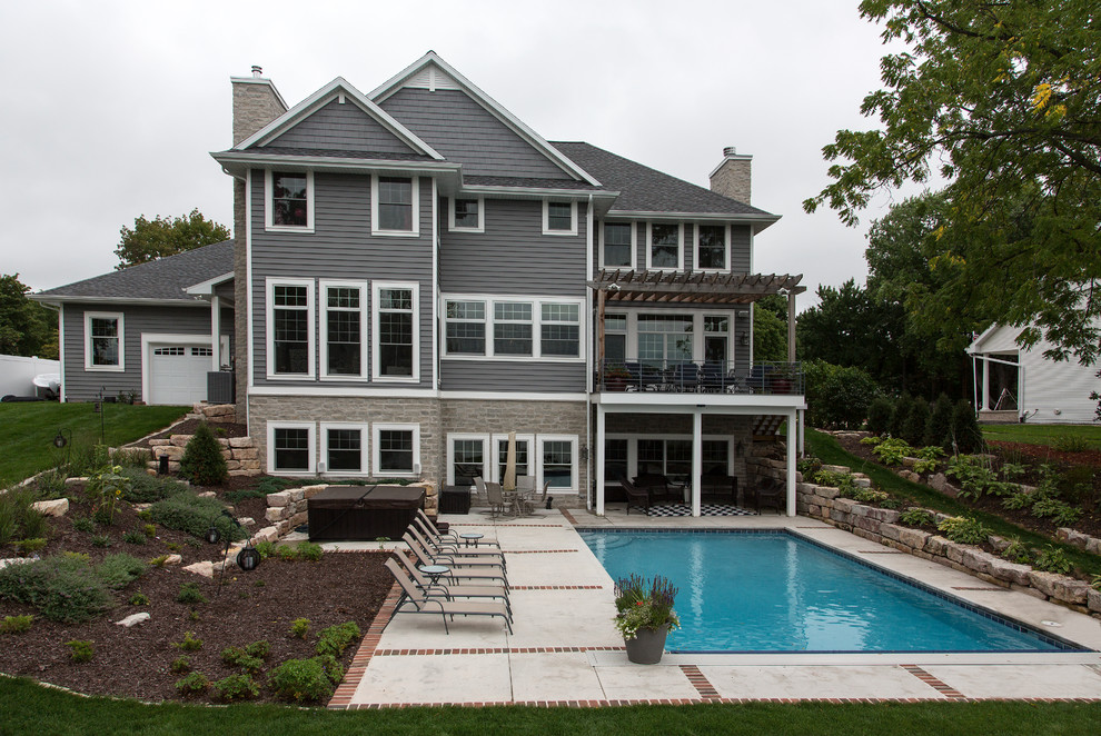 Ispirazione per un'ampia piscina monocorsia stile americano rettangolare dietro casa con una vasca idromassaggio e pavimentazioni in mattoni