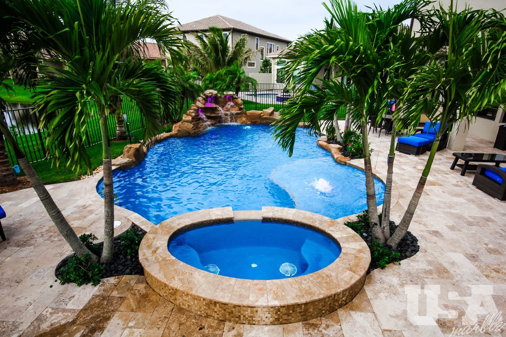 Ejemplo de piscina con fuente elevada grande a medida en patio trasero con adoquines de piedra natural